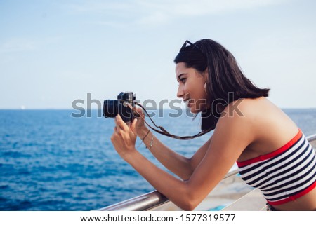 Young Hispanic tourist concentrated on lens focus for photographing horizon skyline of majestic seashore, skilled professional journalist taking pictures during travel vacations near ocean