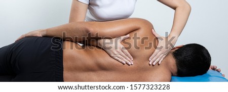 Close up of female osteopath doing shoulder blade therapy on young mam. Royalty-Free Stock Photo #1577323228