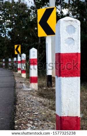 The red and white pillars on the side of the road show signs of curves.
