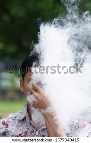 vaping man holding a mod. A cloud of vapor
