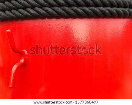 Red color iron steel pole of ship with hook and black rope.