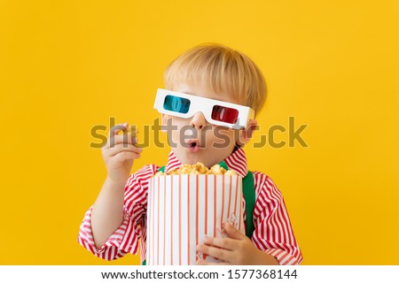 Happy child wearing 3d glasses. Surprised kid against yellow background. Cinema and movie time concept