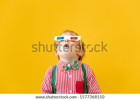 Happy child wearing 3d glasses. Surprised kid against yellow background. Cinema and movie time concept