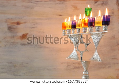 Religion image of jewish holiday Hanukkah background with david star menorah (traditional candelabra) and colorful oil candles
