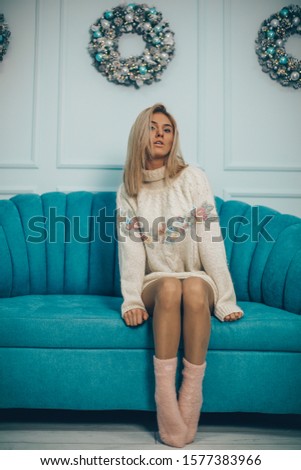 holidays and people concept - happy young woman sitting in bed at home bedroom over Christmas tree lights on background
