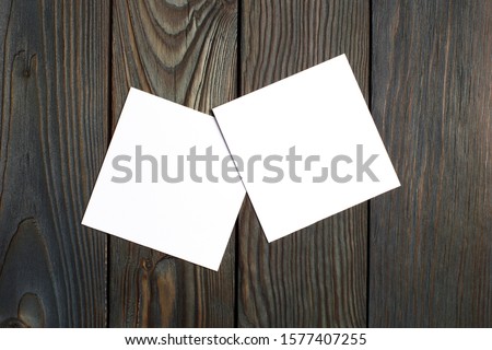 Two square blank cards (business cards, tickets, flyers, invitations, coupons, banknotes, etc.) on dark wooden background
