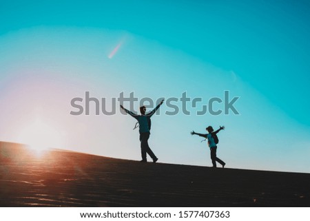 Silhouettes of happy father and son and travel at sunset