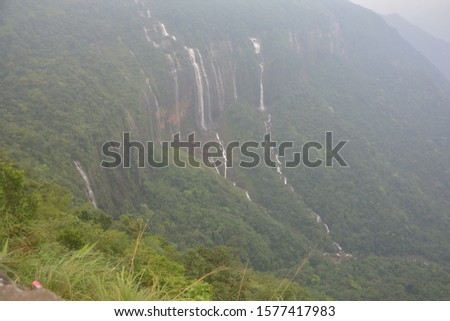The seven sister falls cum Nohsngi Thiang Falls of Cherrapunjee, Shillong with lush green grasses, trees and mountains.