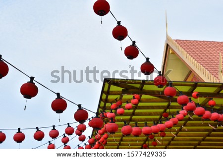 Aligned of red Chinese lanterns hanging with blue sky and green ceiling background.