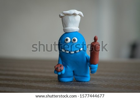 Blue monster chef holding a rolling pin and cookies.