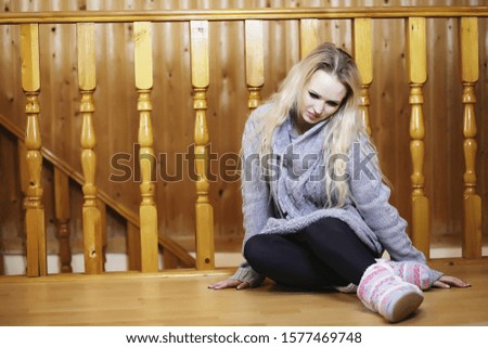 A young girl sits on a ladder in a sweater