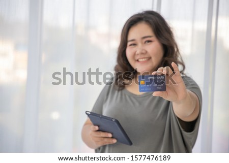 Overweight female (Plus size Asian model , Big woman , fat person) smiling Happy Positive thinking lifestyle concept. Living room background. Shopping Online with Credit card concept. Showing gesture