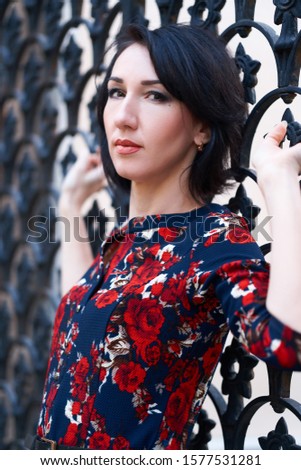Beautiful elegant woman posing near black wrought iron gates