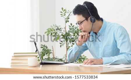 Online lesson concept. Young asian man studying in room. e-learning. Royalty-Free Stock Photo #1577533834