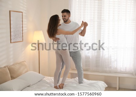 Lovely young couple dancing on bed at home
