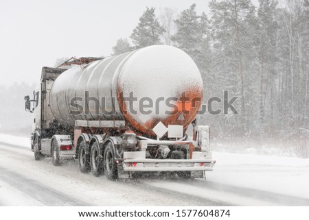 Fuel tanker truck on winter road. Blizzard. 
