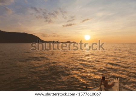  Woman at the stern of the yacht and looks into the distance at sunset.