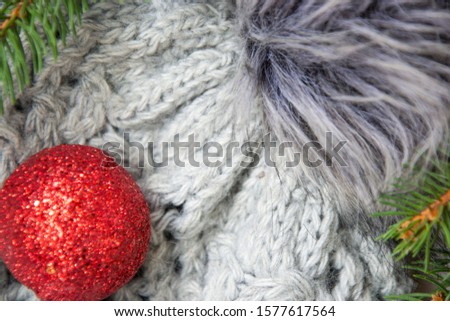 Close-up of gray winter hat with pompom and Christmas toys, pine tree branches, warm  xmas concept