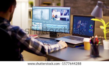 Content creator using modern software for video post production in home office during night hours.