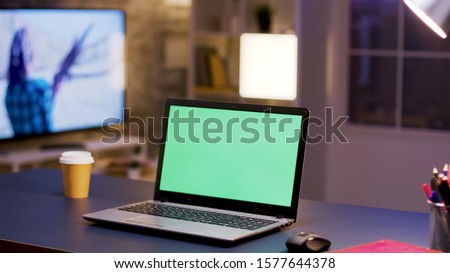 Desktop computer with green screen on home office. Businessman in the background.