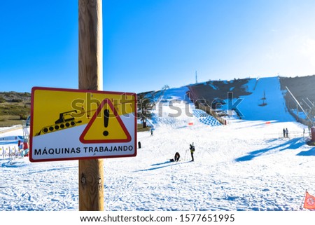 danger sign on which it says "machines at work" in a ski resort in spain full of snow and people