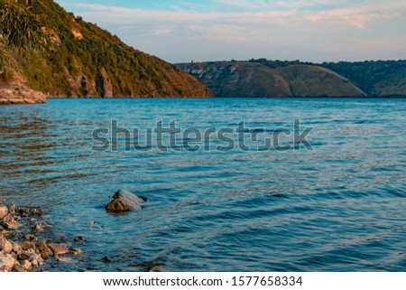 north European scenery landscape picturesque natural environment of stones lake waterfront and mountain hills background in moody weather time 