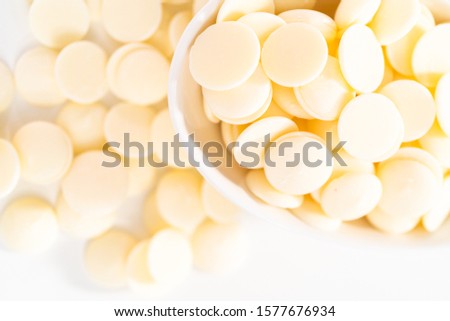White round chocolate chips for melting chocolate shapes on a white background.