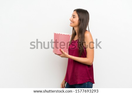 Young woman over isolated white background holding a bowl of popcorns