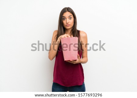 Young woman over isolated white background eating popcorns
