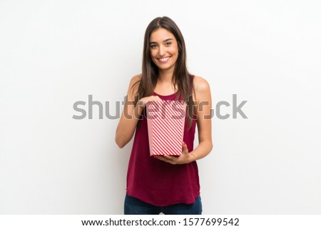 Young woman over isolated white background holding a bowl of popcorns