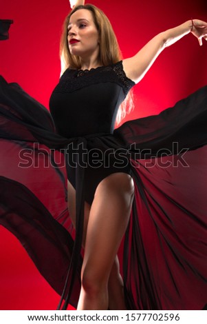 gymnast dancing in a beautiful flying dress on a red background in studio