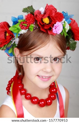 Charming little girl in the Ukrainian national costume smiles on gray background on Holiday