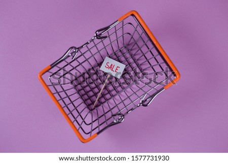 Sale announcement written on the nameplate inside the shopping cart, basket based on the violet background. Low price, special offer concept, advertising. 