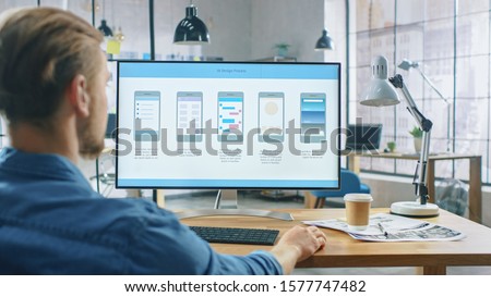 Young Professional Works on a Personal Computer at His Desk in the Creative Office. Notebook Screen Shows Mobile Phone Application Design, Software UI Development. In Background Royalty-Free Stock Photo #1577747482