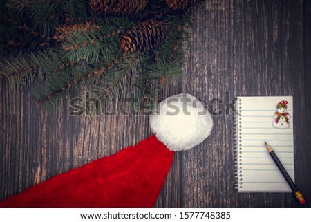 Notes for Santa - notebook and pen on wooden background with Santa's hat