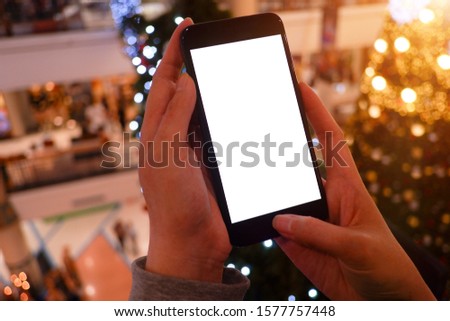 Mockup picture of  woman’s hands or man's hand holding smart phone with white blank screen in modern place.