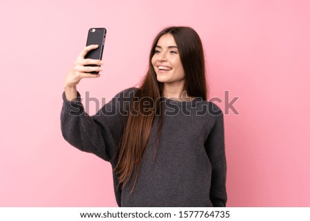 Young woman over isolated pink background making a selfie