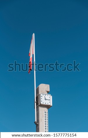 Flag of Gijon, in Asturias, and a clock next to the city beach, on the stairs down to the beach. Spain