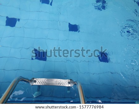 Top view of swimming pool water and ladder and the ceramic tile on the bottol