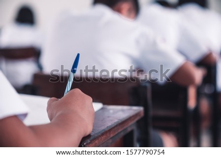 Student doing test or exam  in classroom of school with stress