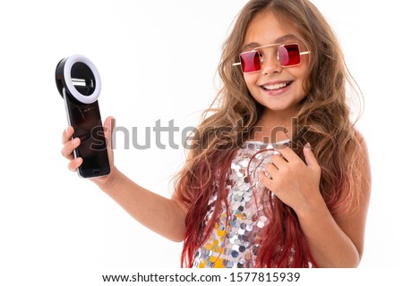 Little pretty caucasian girl do selfie with phone and circle lamp, picture isolated on white background