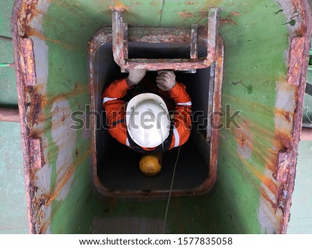 a rescuer climbing down the ladder in the enclosed space to safe and rescue the casualty/injury on board the cargo ship. A part of training and drill for PSC CIC - concentrate inspection campaign.  Royalty-Free Stock Photo #1577835058