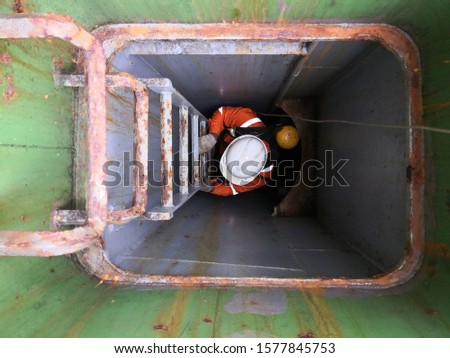 a man with self contained breathing apparatus and lifeline is climbing on the ladder into an enclosed space on cargo ship for training and drill during PSC CIC 2019 -  concentrate inspection campaigns Royalty-Free Stock Photo #1577845753