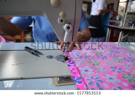 Female hands stitching white fabric on professional manufacturing machine at workplace. seem to be stressful.