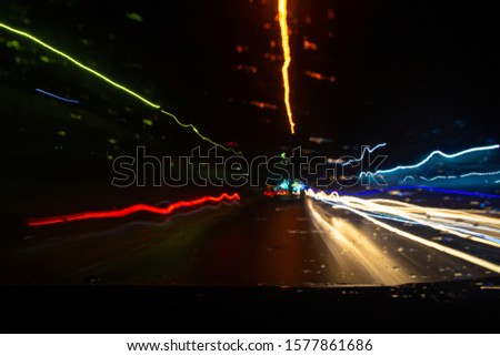 Blured or not focus road view with traffic light trails at rain, view from inside car
