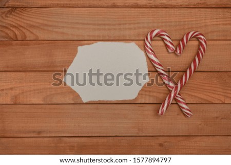 Beautiful striped hard candy cane staff on a red wooden table background.