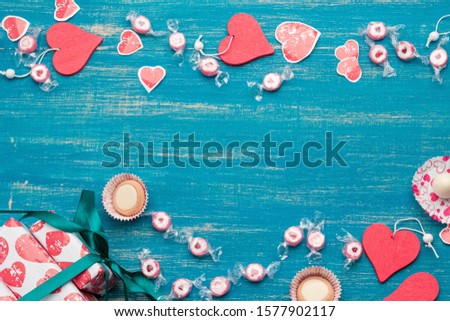 on a blue shabby background, wrapped gifts in paper with an ornament of hearts and wooden red hearts and sweets