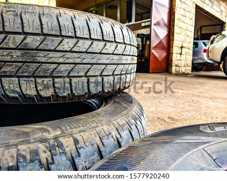Car tires stacked on each other in a car repair mechanic shop, season of changing the tires is coming, important for safety on the roads