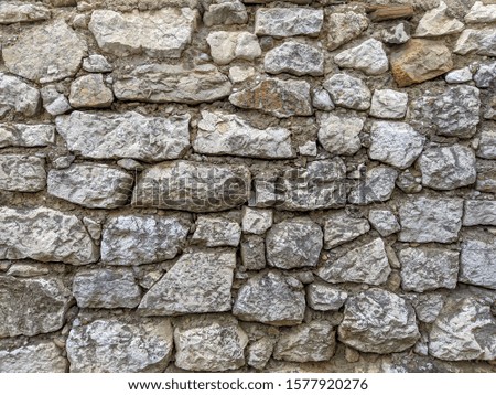 Old style retro and traditional way of building a wall with uneven stones and rocks glued with cement with sign of damage making a cool background wallpaper
