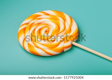 Colorful round Lollipop, on mint blue background. Minimal concept with copy space.